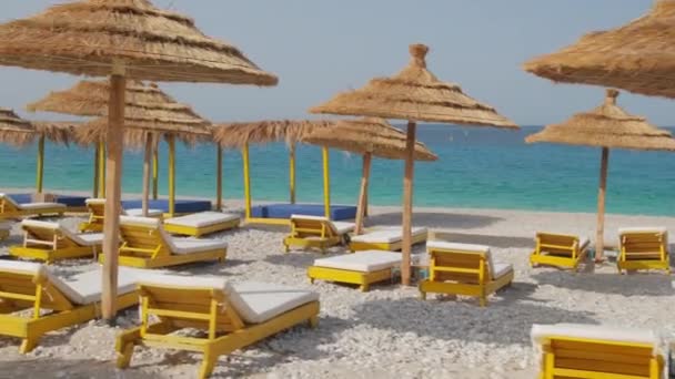 Камера повільно рухається через красивий пляж з парасольками і лежаками — стокове відео
