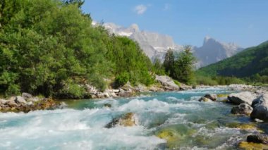 Arka planda görkemli kayalık dağlar olan hızlı dağ nehri suyu
