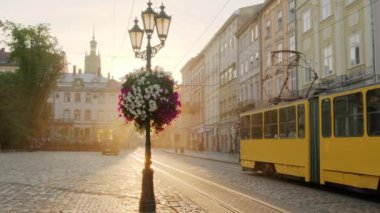Ukrayna, Lviv 'de güneş doğarken geleneksel sarı tramvaylı Pazar Meydanı