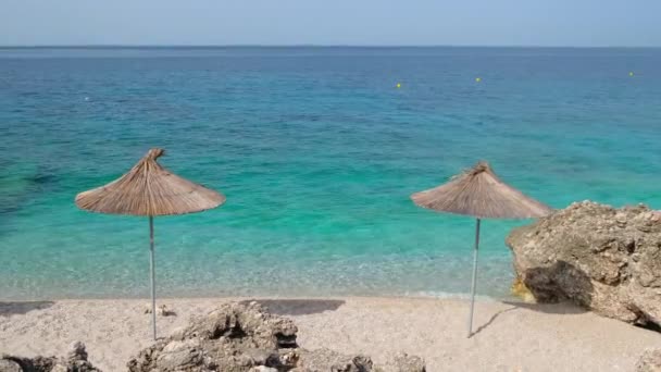 Gyönyörű, üres vad strand napernyőkkel és gyönyörű, nyugodt tengervízzel — Stock videók