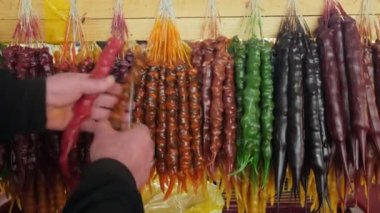 Satıcı, Tiflis, Georgia 'daki gıda pazarında taze Churchkhela tatlısını kesti.