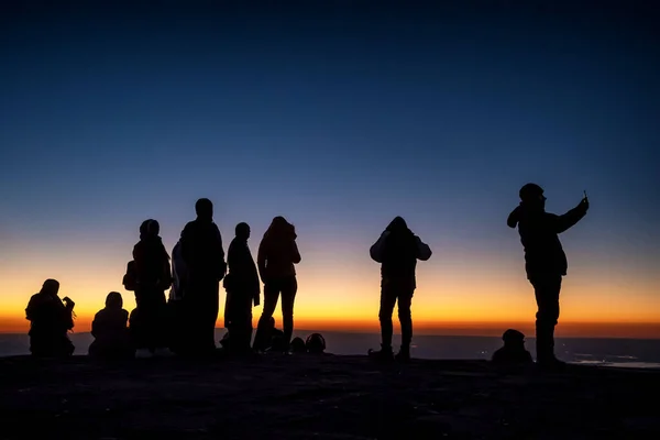 Silueta de personas no identificadas en la cima de la montaña esperando el amanecer —  Fotos de Stock