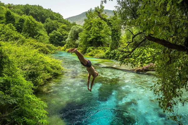 Unidentified man jump into the beautiful turquoise spring Blue Eye or Syri i Kalter near Muzine town in Albania. — Stock Photo, Image