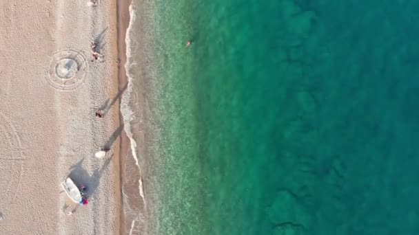 Légi felvétel az emberek pihenés egy üres tengerparton, nyugodt tengervíz — Stock videók