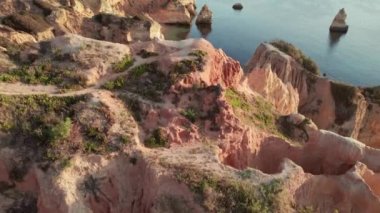 Portekiz 'in Algarve ilindeki Lagos kasabası yakınlarındaki Praia do Camilo plajı. Güneşin doğuşundaki güzel Camilo plajının insansız hava aracı görüntüleri. Tahta köprüsü olan kayalık gölde beyaz kumsal.
