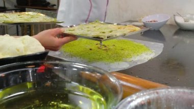 Türkiye 'nin Doğu Anadolu kentindeki Gaziantep Kafe' de geleneksel Gaziantep tatlısı Katmer pişirme süreci. Kimliği belirsiz şef filo hamurunu fıstık tozu ve kayak peyniriyle dolduruyor. 