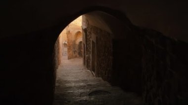 POV, Türkiye 'nin Mardin kentinin tarihi eski kaldırım taşı caddelerinde kemerli karanlık bir geçitten geçiyor. Mardin 'in tarihi evlerinin altında kemer ve tünel olan yaya merdivenleri sokağı..