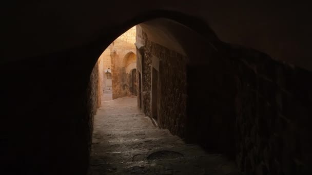 在土耳其马尔丁古老的鹅卵石街道上 Pov走过一条拱门的黑暗通道 马尔登老城历史建筑下方有拱门和隧道的步行街 — 图库视频影像