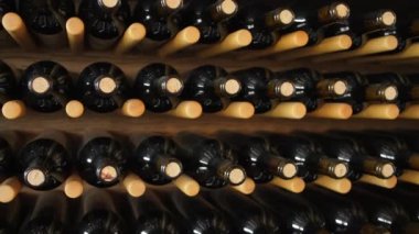 Şaraphanedeki şarap şişeleri. Şarap rafında pahalı şarap şişeleri var. Şarap mahzeninde etiketsiz şişeler. Yavaş sabit görüntü