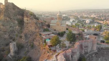 Tbilisi cityscape at sunset, Georgia. Flying around the famous Narikala Fortress with city center and Kura river at background in Tbilisi. Aerial drone footage of the Georgian capital.