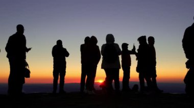 Silhouette of unidentified people at the top of Nemrut mountain watching sunrise in Eastern Anatolia, Turkey. Abstract footage with silhouette of crowd at dawn. 