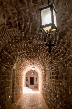 Doğu Türkiye, Mardin 'deki Mor Hananyo Manastırı' nın eski tünel geçidi. Christian Cross odaklı fener. Sığ DOF