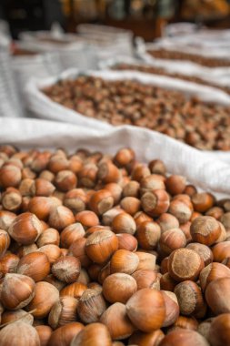 Fresh hazelnuts in shells for sale in outdoor food market. Lots of Hazelnuts in big sacks on the market. Hazelnuts in shell close-up. Shallow DOF