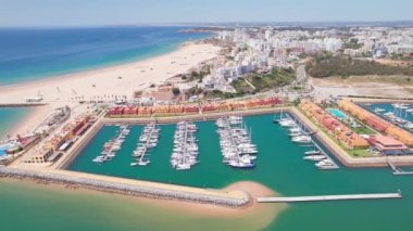Güney Portekiz 'in Algarve bölgesindeki Praia da Rocha ve Portimao tatil köylerinin hava manzarası. Lüks marinalı İHA görüntüleri, güzel uzun beyaz kumlu plaj ve Portimao şehir manzaralı.