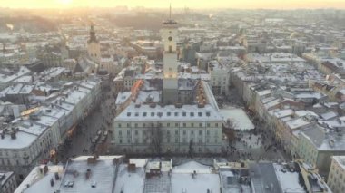 Aerial drone view of Lviv cityscape in winter, Western Ukraine. Lviv old town covered with snow. Central market square with a City Hall, old churches and historic buildings in winter at sunset