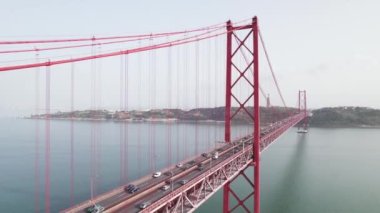 Aerial view of the 25 de Abril Bridge in Lisbon, Portugal. Cars driving along the famous bridge connecting the city of Lisboa to the municipality of Almada on the left bank of the Tejo river.