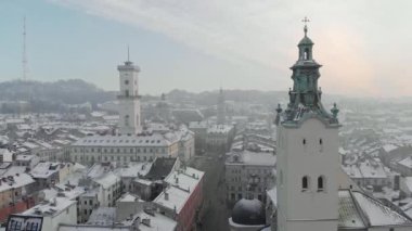 Aerial drone view of Lviv cityscape in winter, Western Ukraine. Lviv old town covered with snow. Central market square with a City Hall, old churches and historic buildings in winter at sunset