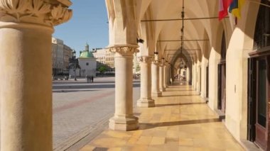 Camera slowly moves along Krakow cloth hall on the main market square at sunrise in Cracow, Poland. Arched passageway of the historic Sukiennice building.