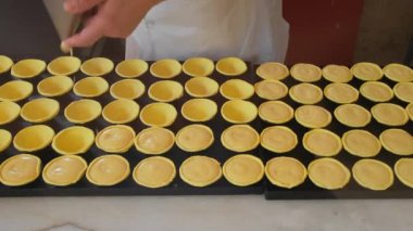 Pastry chef makes and fills traditional Portuguese pastel de nata pastries with custard. Process of cooking famous portuguese dessert pastel de nata custard tart in bakery