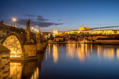 Charles bridge and the Prague castle in the evening, Czech Republic. Night view of a Prague cityscape with Prague Castle and Karlov most bridge across Vltava river.