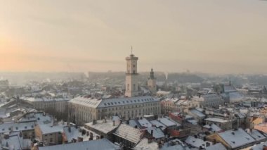 Aerial drone view of Lviv cityscape in winter, Western Ukraine. Lviv old town covered with snow. Central market square with a City Hall, old churches and historic buildings in winter at sunset