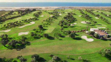 Aerial view of a luxury golf field at sea coast in Portugal. Bird eye view over golf course. Beautiful golf playground field with hills, sand areas and trees. Luxury travel destination