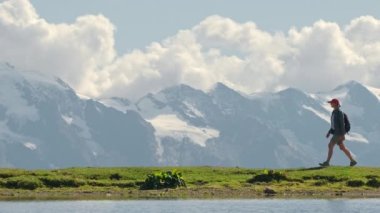 Woman hiking near high altitude Koruldi lakes at sunny day with majestic Caucasus mountains at background, Svaneti region, Georgia. Slow motion video