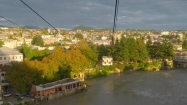 Kutaisi, Georgia - Spetember 26, 2021: View from the vintage cable car cabin with beautiful Kutaisi cityscape at sunset in Georgia. Old cable car road over the Rioni river and Bagrati Cathedral church