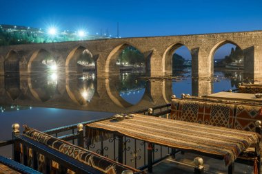 Diyarbakir, Turkey historic ten-eyed bridge view Ongozlu Kopru over the Tigris river at night, Turkey. Outdoor cafe near the historic bridge
