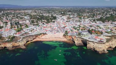 Portekiz 'in Algarve şehrindeki Carvoeiro şehrinin manzarası. Portekiz kıyısında renkli evleri olan Carvoeiro kasabasındaki plaj manzarası. Hava aracı görüntüleri.