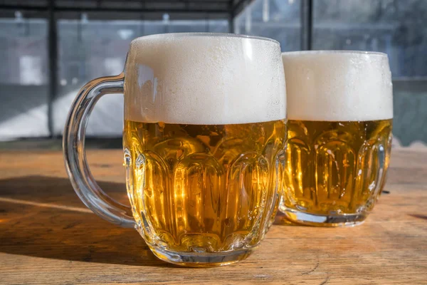 Dwa Kubki Jasnego Piwa Pianką Drewnianym Stole Prawdziwym Pubie Piwnym — Zdjęcie stockowe