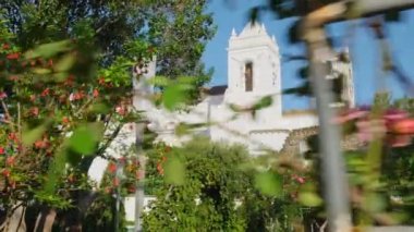 St. Marys Kilisesi, Igreja de Santa Maria do Castelo, Tavira, Algarve, Portekiz. Yavaş çekim, sabit çekim. Güneşli bir günde Tavira Kalesi 'nde çiçek bahçesi. 