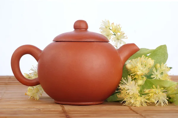 Earthenware teapot with linden tea and flowers on white background Royalty Free Stock Images