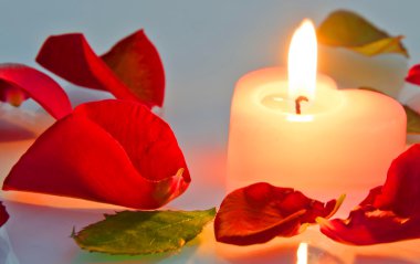 gül yaprakları kalp şeklinde yanan bir mum