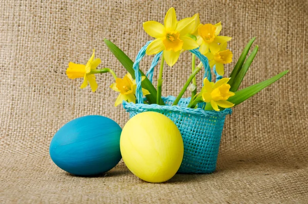 Easter eggs and daffodils in a basket — Stock Photo, Image