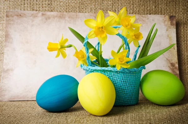 Easter eggs and daffodils in a basket — Stock Photo, Image