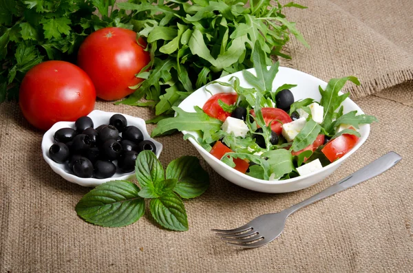 Ensalada griega en ensaladera blanca con cubiertos y verduras en s —  Fotos de Stock