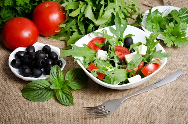 Ensalada griega en ensaladera blanca con cubiertos y verduras —  Fotos de Stock