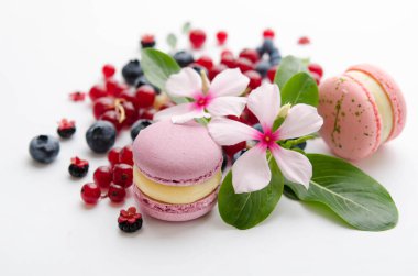 Kırmızı ve mavi böğürtlen serpintisi. Beyaz çiçek ve yeşil yapraklar. Mor ve pembe badem kurabiyeleri.