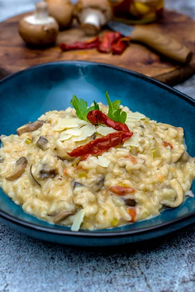 Mantarlı risotto ve mavi kasede kurutulmuş domates.