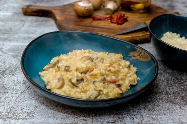 Mantarlı risotto ve mavi kasede kurutulmuş domates.