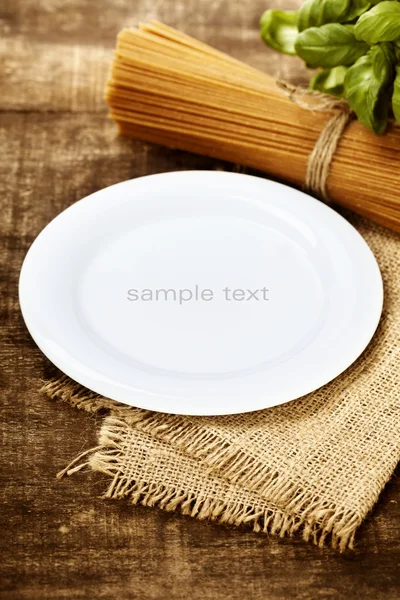 Whole wheat spaghetti, ingredients and plate for text — Stock Photo, Image