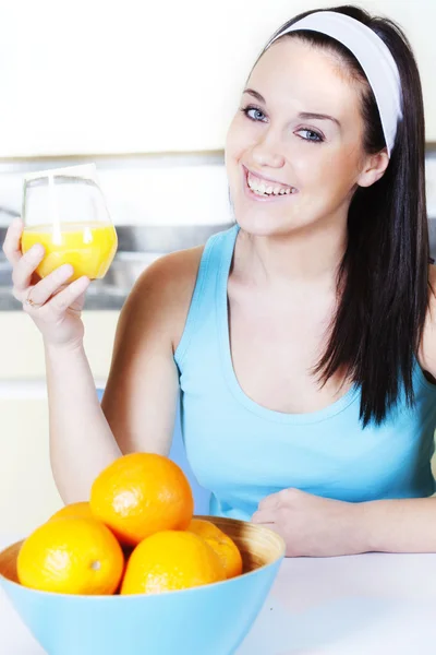 Lächelnde Frau mit Orangensaft in der Küche — Stockfoto