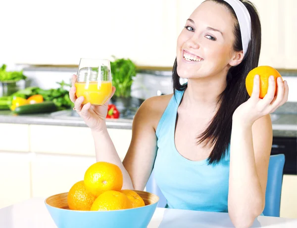 Femeia zâmbitoare cu suc de portocale în bucătărie — Fotografie, imagine de stoc