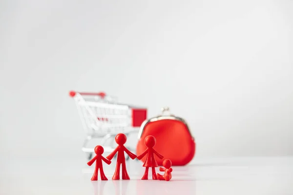 Miniatuur plastic figuren familie met kinderen, Metallic winkelwagen trolley en Red Coin portemonnee op lichtgrijze achtergrond met kopieerruimte, winkelen en familie financiën concept — Stockfoto