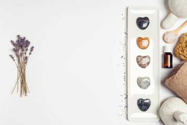 Beyaz mermer zemin üzerinde doğal kozmetik ürünleri ve gri taşlar ile düz bileşim yatıyordu
