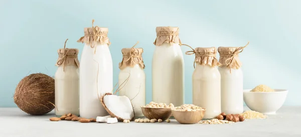 Veganistische melk op basis van niet-zuivelgewassen in flessen op blauwe achtergrond. Alternatieve lactosevrije melkvervanger, banner — Stockfoto