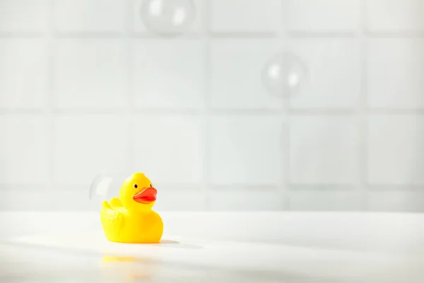 Mignon canard en caoutchouc sur comptoir de salle de bain blanche avec espace pour le texte — Photo
