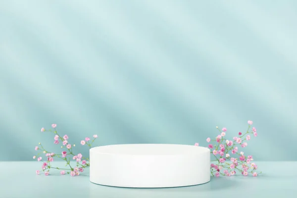 Abstrakcyjne puste białe podium z geometrycznymi cieniami i różowymi kwiatami na niebieskim tle. Stojak modelarski do prezentacji produktu. Renderowanie 3D. Koncepcja minimalna — Zdjęcie stockowe