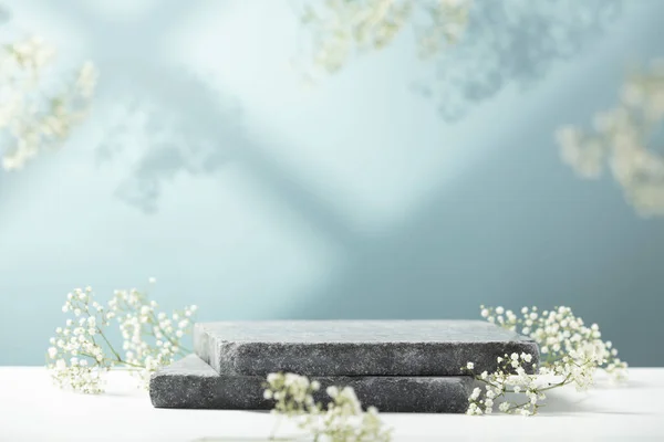 Pedestal de granito plano e flores brancas sobre fundo azul. Mostra para produtos cosméticos. Publicidade de produto. Design de estilo de layout. — Fotografia de Stock